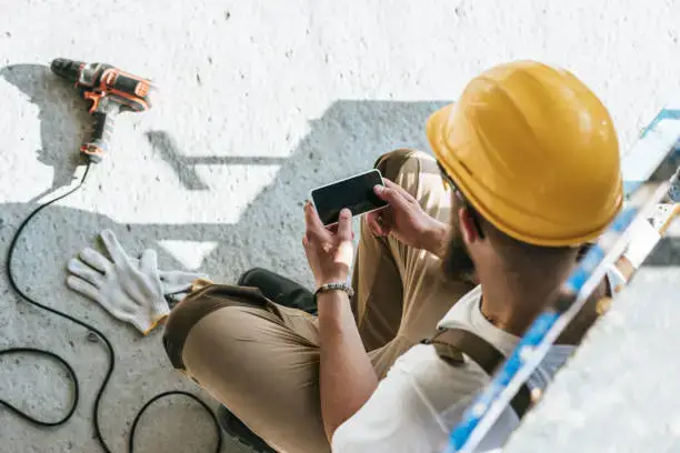 Construction worker on break check mobile phone