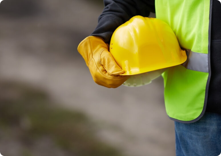 Man holding a yellow helmet, representing the construction industry and professionalism