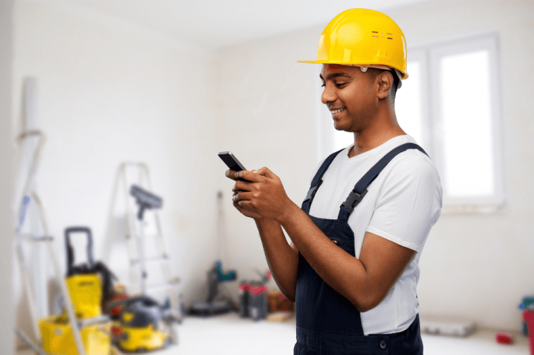 Mobile Plumber holding phone on the job and managing his jobs online