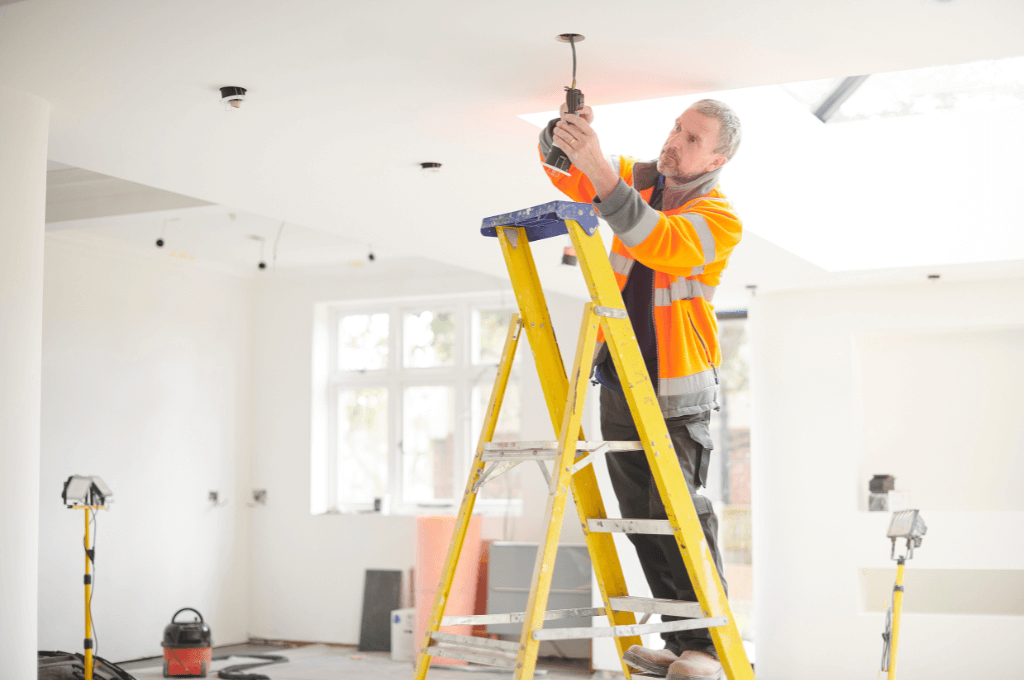 Electrician installing new ceiling lighting in a residential property